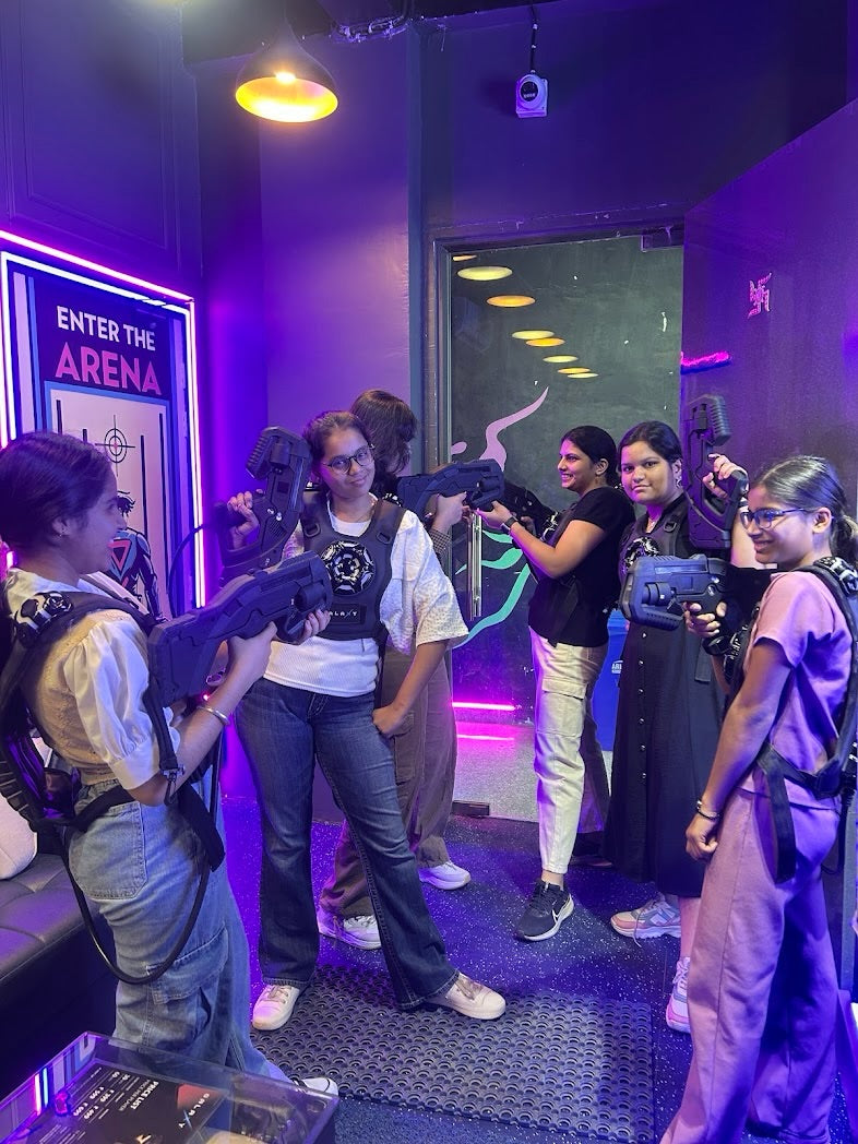 Young people in a laser tag arena, holding phasers and wearing vests, ready to play.