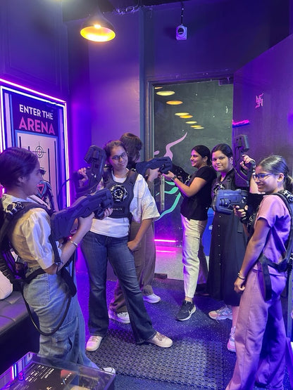Young people in a laser tag arena, holding phasers and wearing vests, ready to play.