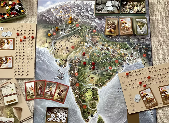 Board game laid out on a carpet, depicting a map of India with game pieces and cards.