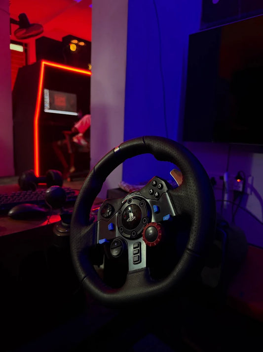 A gaming steering wheel in a dimly lit room with red and blue neon lights.