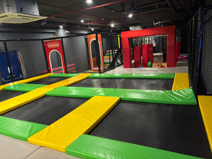 Indoor trampoline park with colorful padding and netting.