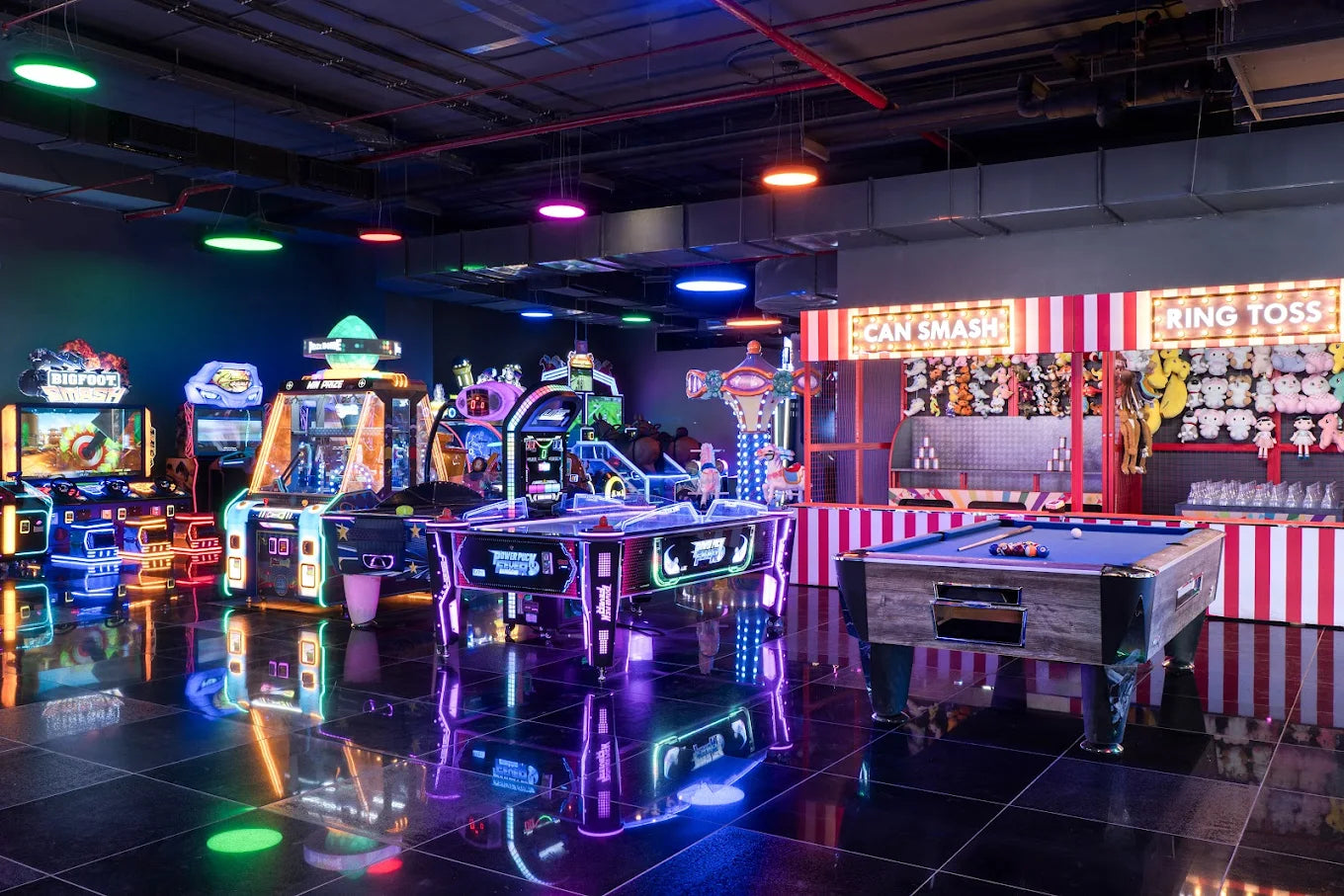 An arcade with glowing games and a pool table, filled with young people enjoying the entertainment.