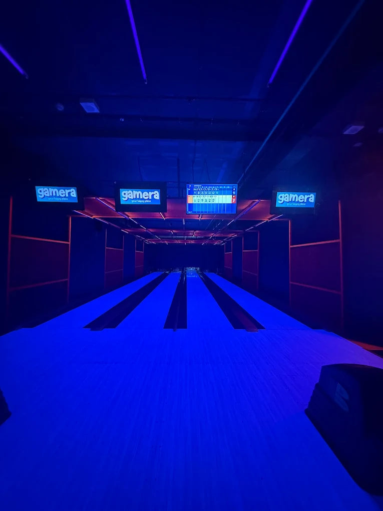 A neon-lit bowling alley with glowing blue lanes and scoreboards.