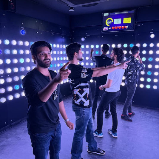 Young adults playing a light-up interactive game in a dark room.