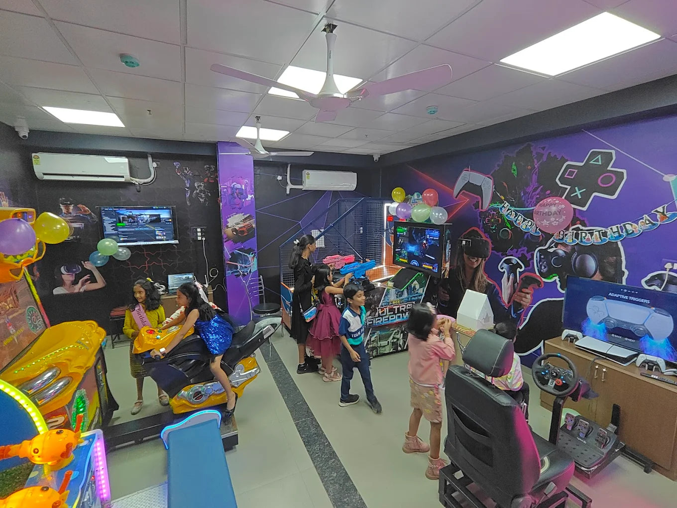 Children play video games at a birthday party in an arcade, with VR headsets and racing simulators.
