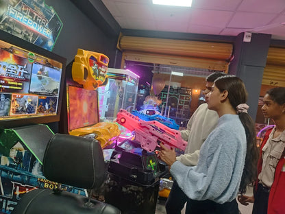Young people play a shooting game at an arcade, holding colorful toy guns.