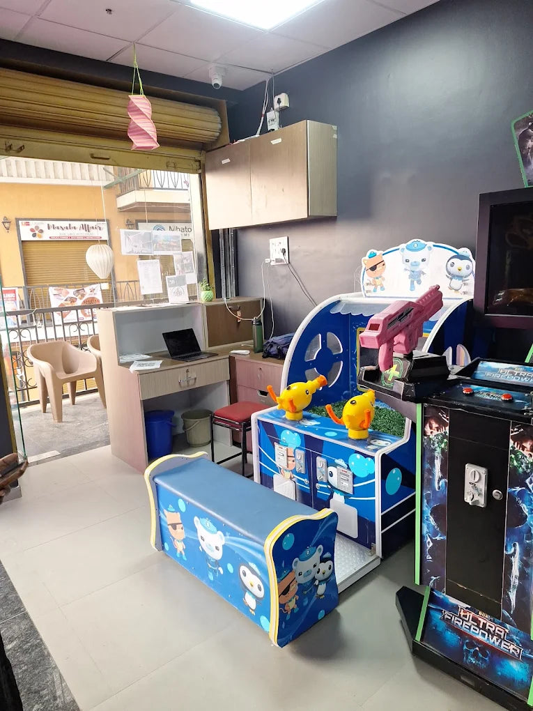 An indoor arcade with children's games and a seating bench.