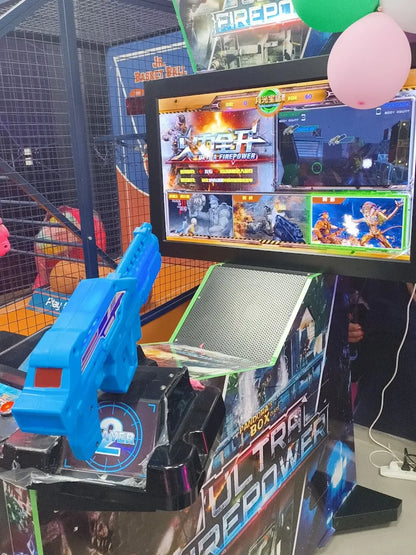 A blue toy gun is attached to an arcade game cabinet with a screen displaying a video game.