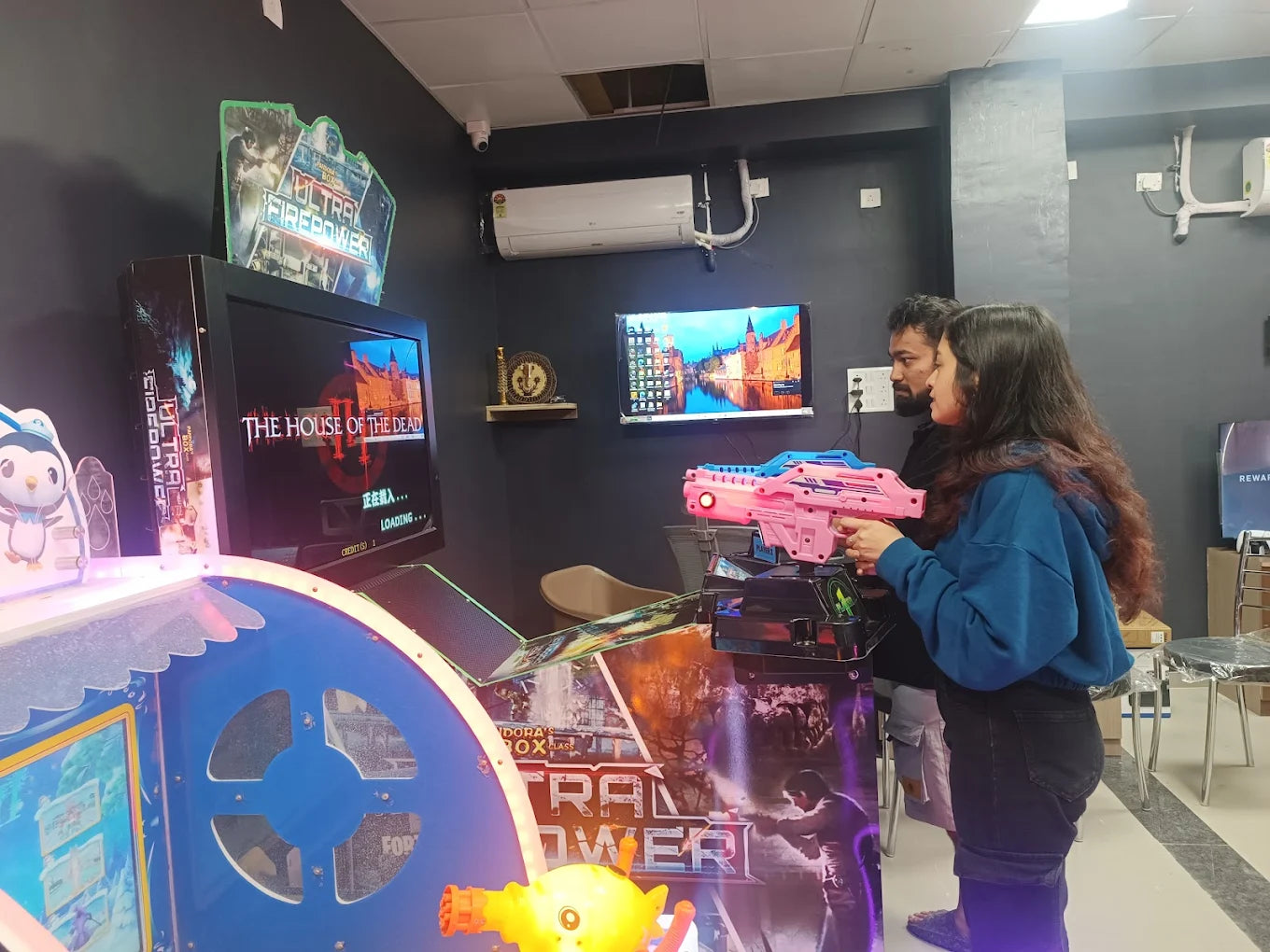 Two young adults play a shooting game at an arcade, holding toy guns in front of a screen.