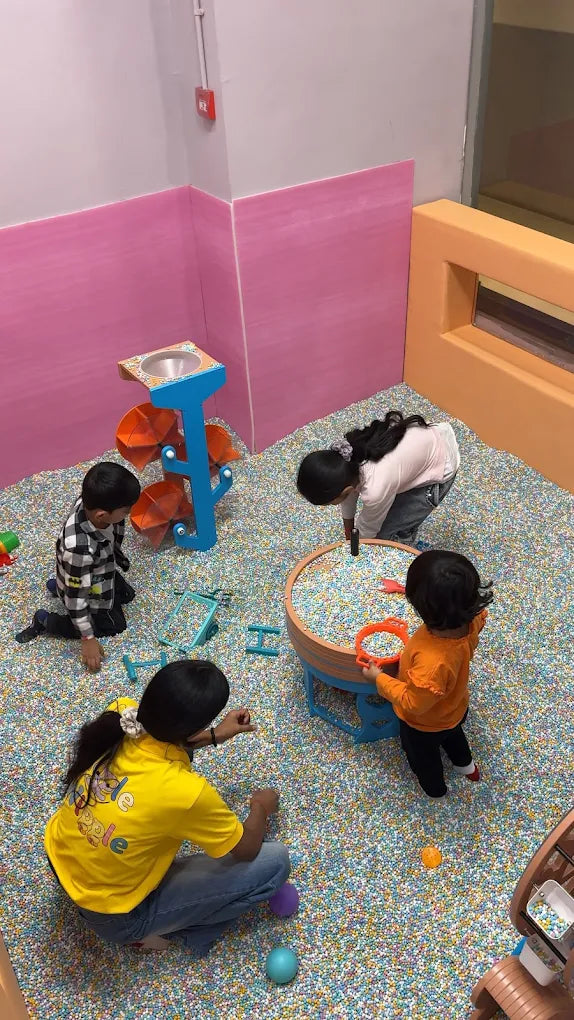 Children play in a ball pit with colorful balls and interactive toys.