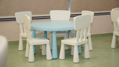 A round, light blue table with white chairs for children in a classroom.
