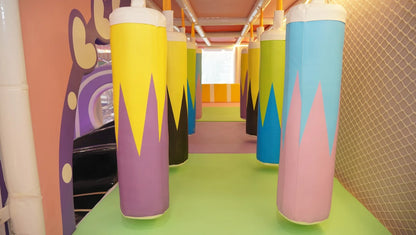 A colorful indoor playground with hanging punching bags and soft flooring for children.