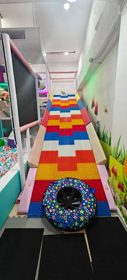 A colorful indoor playground slide with a tube at the bottom, designed for children.