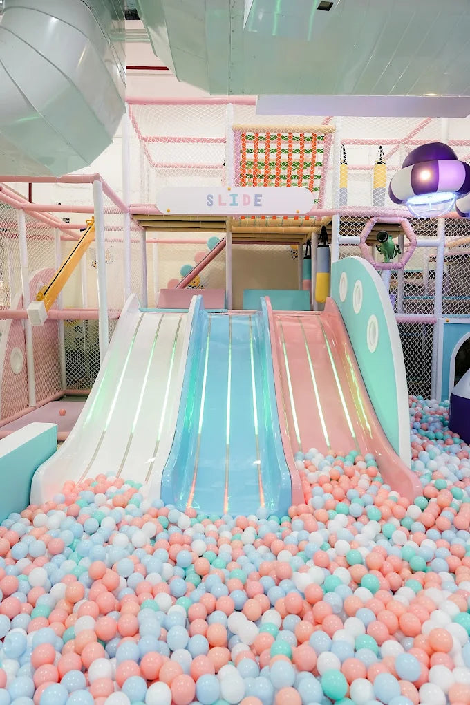 A pastel-colored indoor playground with slides and a ball pit for children.