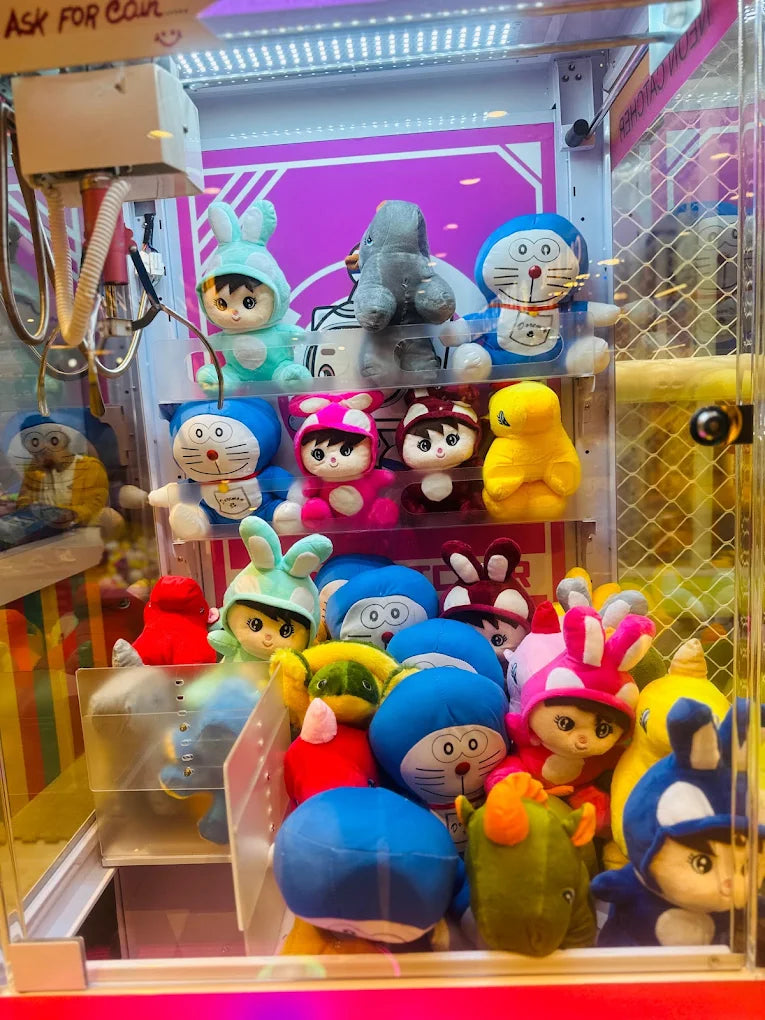 A claw machine filled with plush toys, including Doraemon and characters in bunny costumes.
