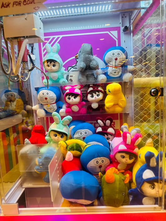 A claw machine filled with plush toys, including Doraemon and characters in bunny costumes.