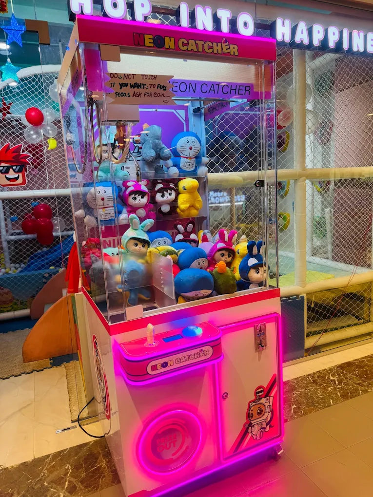 A neon claw machine filled with plush toys, likely in an arcade or entertainment center.