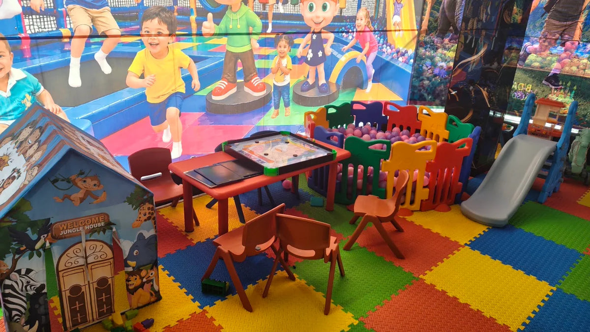 Children play in a colorful indoor playground with a ball pit, slide, and jungle-themed playhouse.