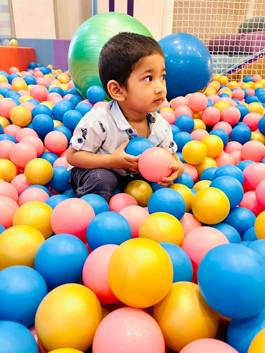 Child playing in a ball pit filled with colorful balls