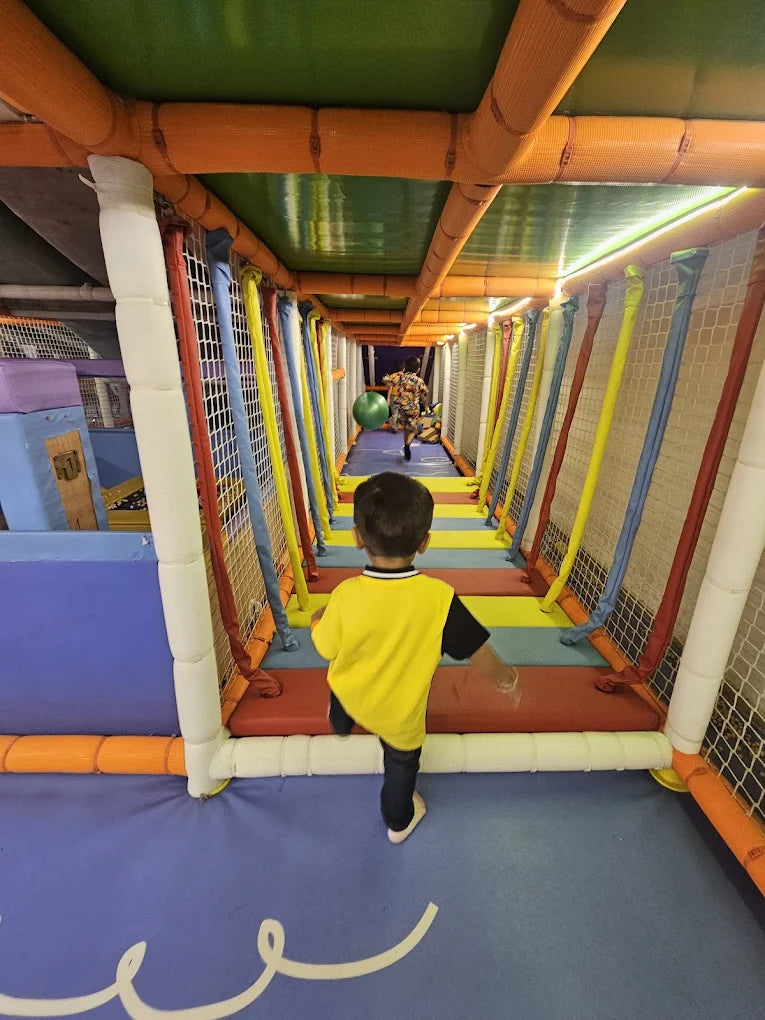Child in a colorful indoor play area with soft walls and a blue floor.