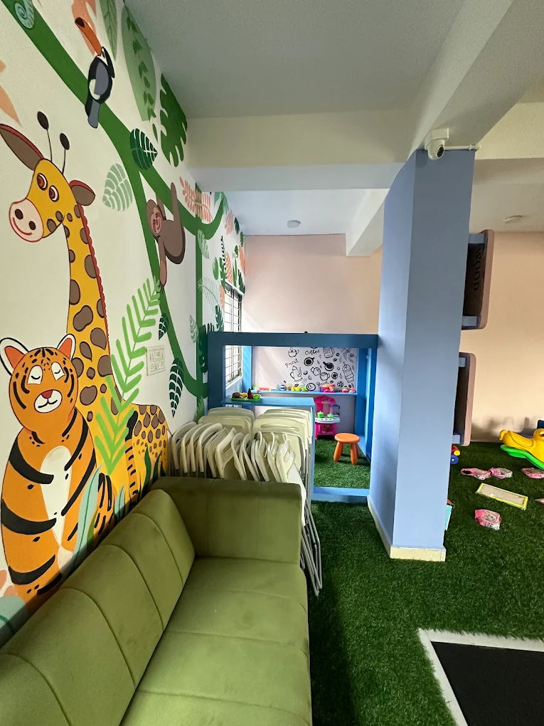 A brightly decorated playroom with a jungle theme, featuring a green couch, artificial grass, and a play structure.
