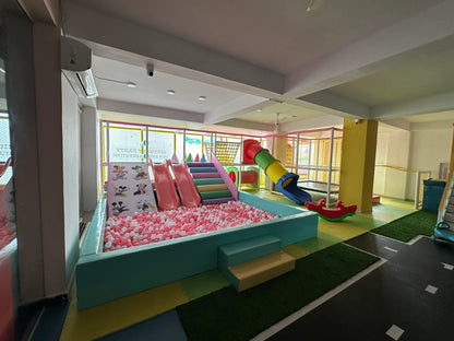 A colorful indoor playground with a ball pit, slides, and a tube slide for young children.