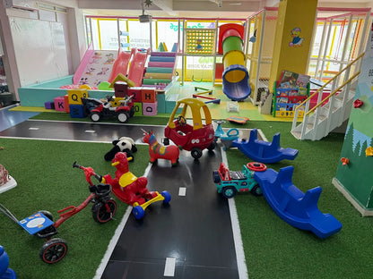 A colorful indoor playground with slides, ball pit, and ride-on toys for young children.