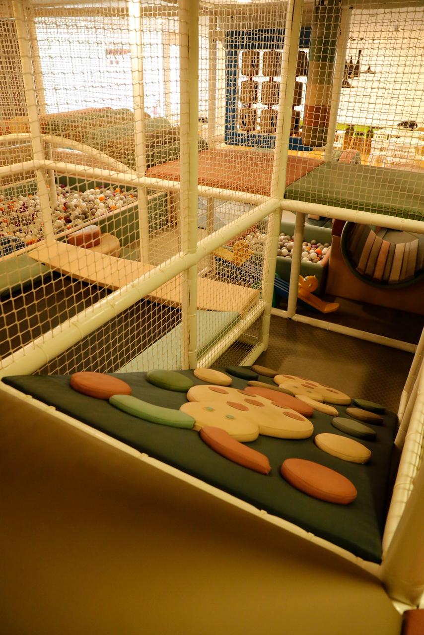 A colorful indoor playground with ball pits and soft play structures for children.
