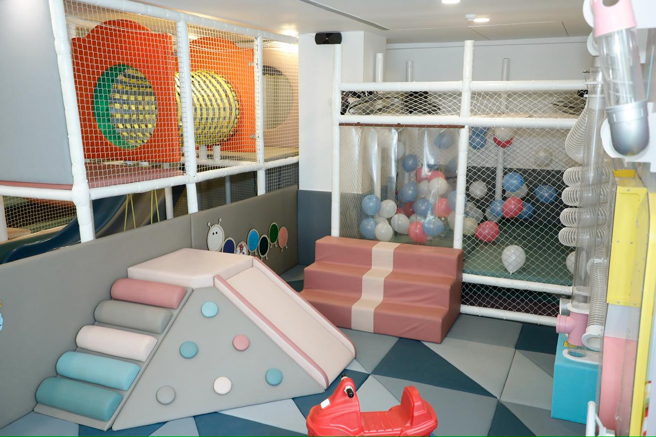 A colorful indoor playground with soft play structures, a ball pit, and slides for young children.