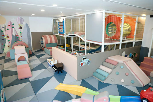 A colorful indoor playground with soft play structures and a ball pit for young children.