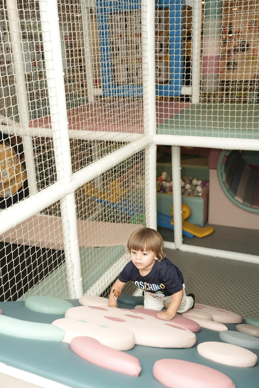 A young boy crawls on a soft play mat in a colorful indoor playground.