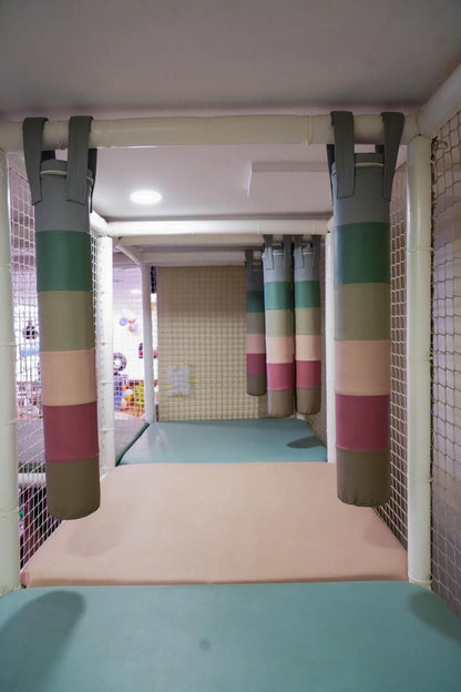 Soft play area with hanging padded cylinders and padded floors.