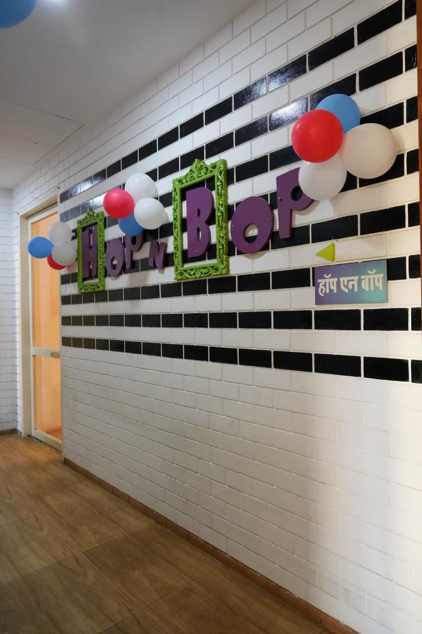 Balloons and "Hop N Bop" sign decorate a white brick wall with black stripes.