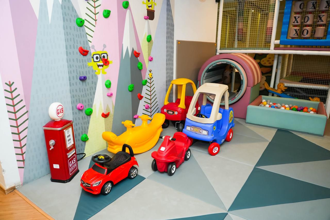 A colorful indoor playground with ride-on toys and a ball pit for young children.