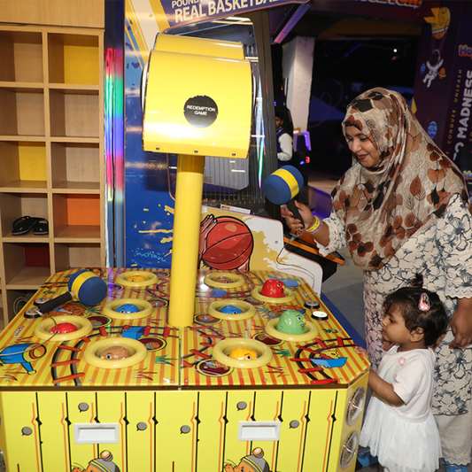A woman and a young child play a whack-a-mole arcade game.