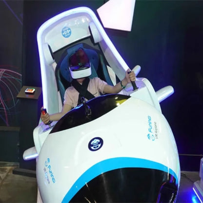 A person in a VR headset pilots a simulated airplane ride. The ride features a cockpit with joysticks and a large white exterior.