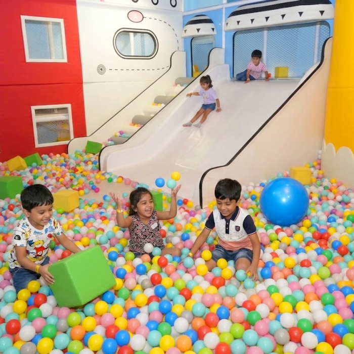 Children play in a ball pit with a slide.
