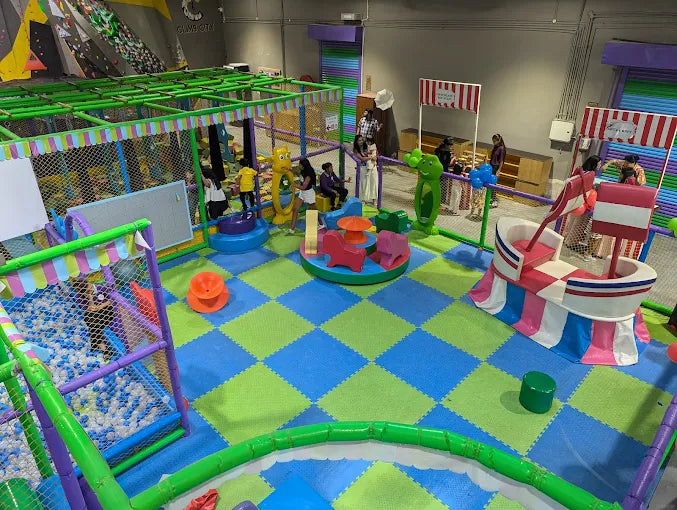 Colorful indoor play zone with interactive structures, ball pit, and children engaged in fun activities supervised by adults