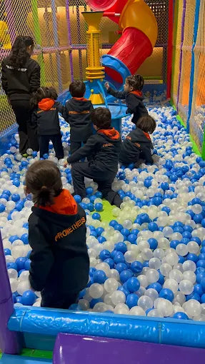 Children playing in a ball pit with colorful playground equipment in the background