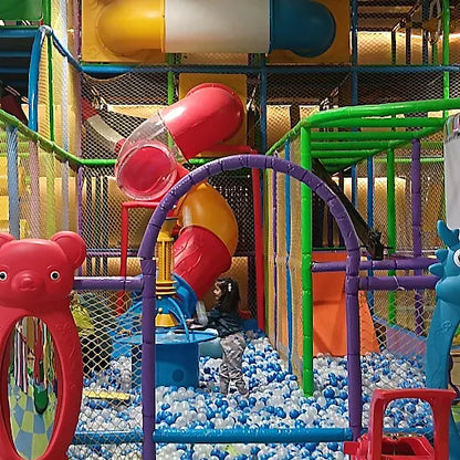 Indoor play area with colorful climbing tubes, ball pit filled with white and blue balls, and soft padded structures