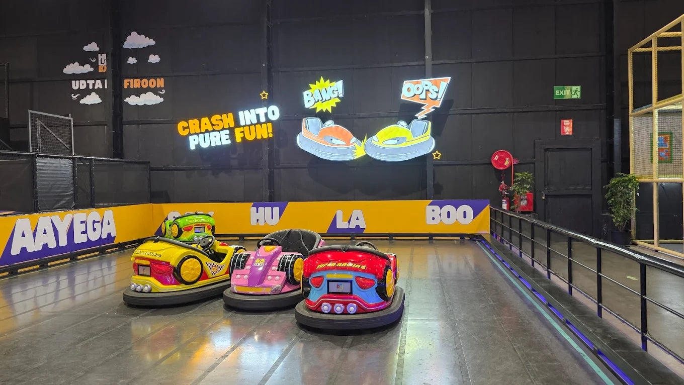 Bumper cars in an indoor amusement park with colorful decorations and playful signage.
