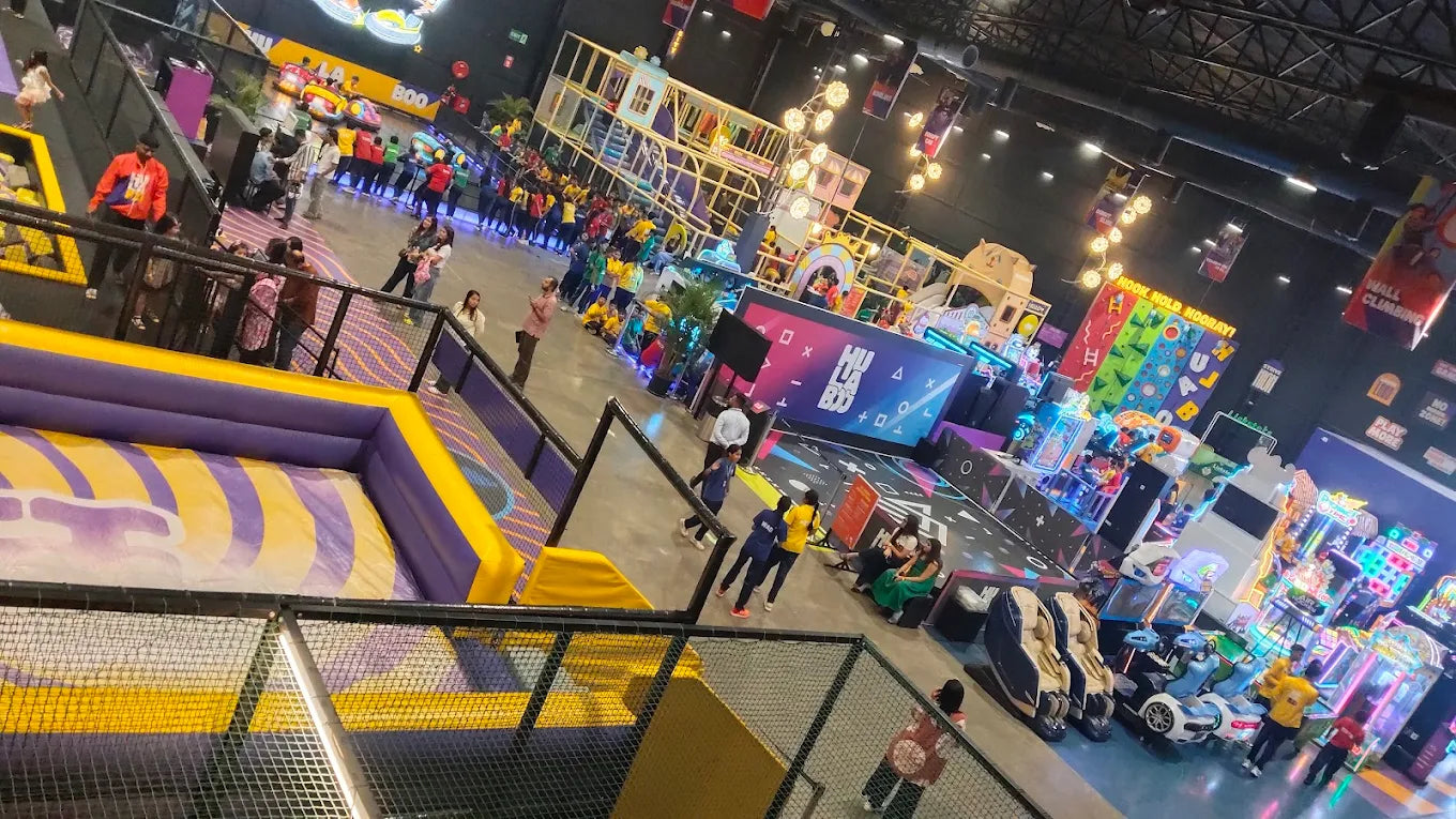 An indoor amusement park with children and adults enjoying various attractions like trampolines and arcade games.