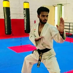 Person in a martial arts uniform with a black belt on a colorful mat