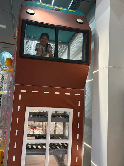 Playground structure resembling a fire truck with a child inside, reflecting on the window.
