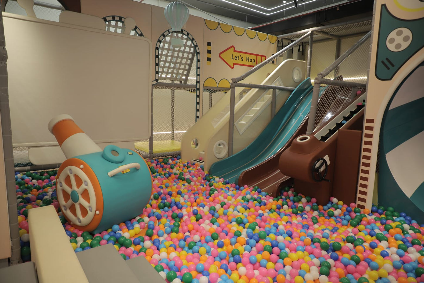 Children's play area with colorful ball pit, slide, and toy cannon.
