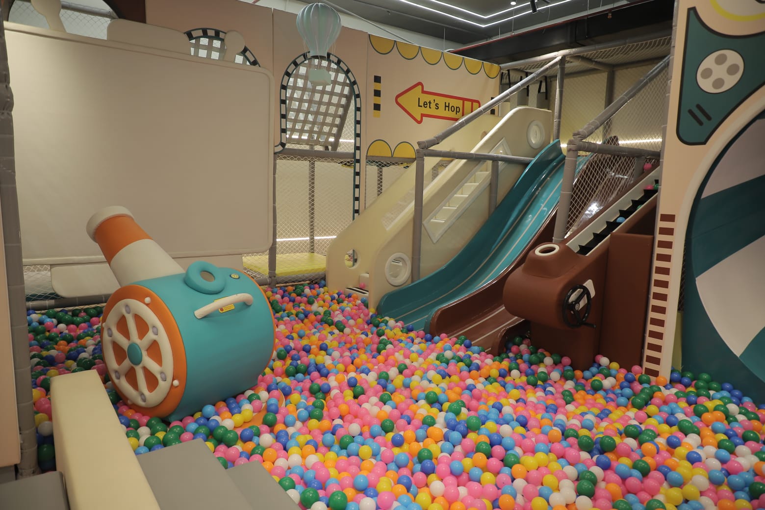 Children's play area with colorful ball pit, slide, and toy cannon.