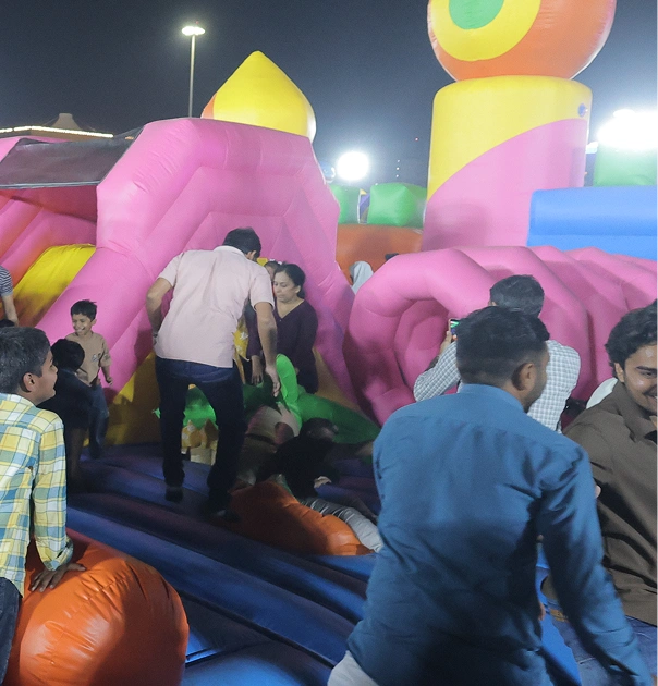 People of various ages enjoy a large, colorful inflatable playground at night.