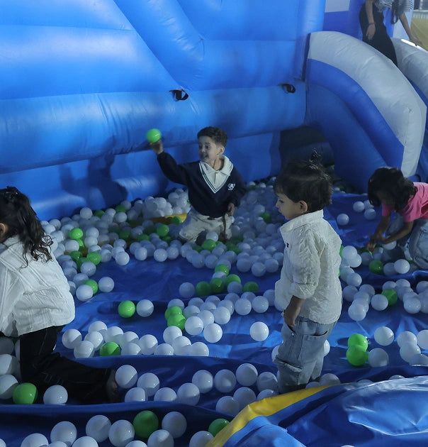 Children play in a blue ball pit inside an inflatable structure.