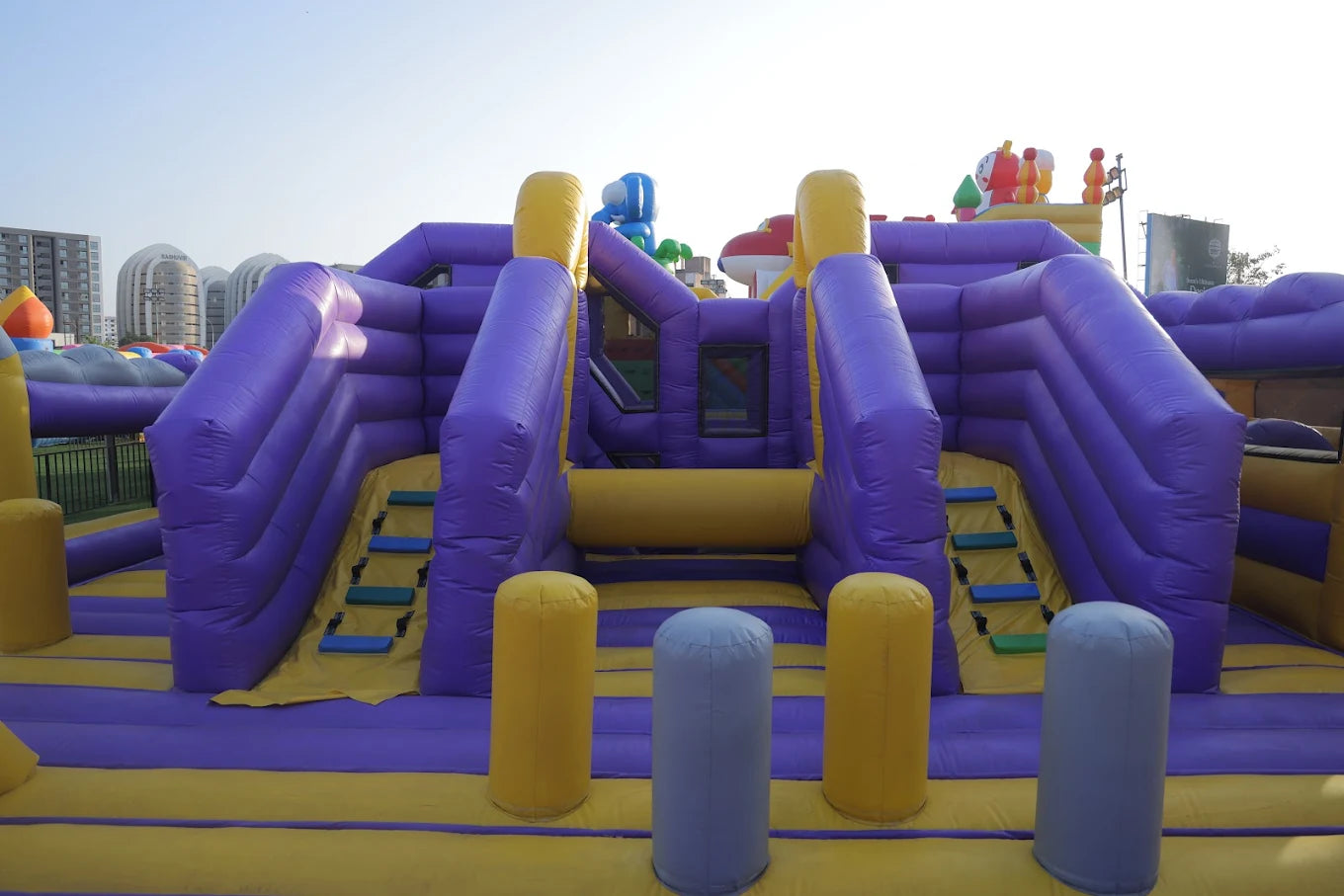 A large purple and yellow inflatable playground with slides and climbing areas for children.
