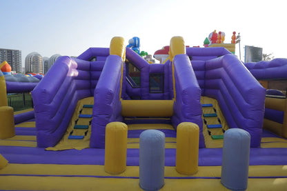 A large purple and yellow inflatable playground with slides and climbing areas for children.